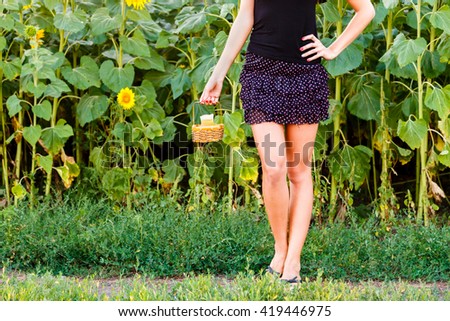 Young woman holding a wicker basket with a jug of sunflower oil on the background of the field. harvesting concept