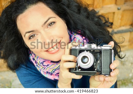 Happy beautiful brunette taking pictures outdoor, retro color