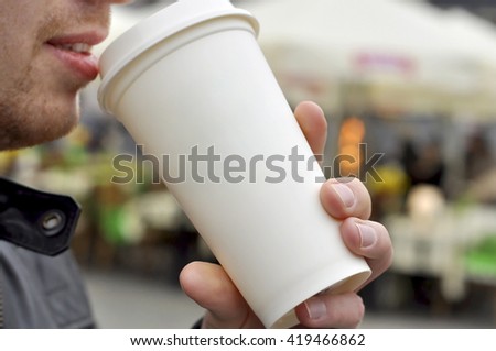 A man holding a white paper cup of water, coffee or tea - toned picture