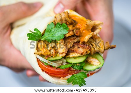 Shawarma - the best street food . Eastern cuisine. Meat and vegetables - tasty and healthy . Close- up of a man's hands.
 Royalty-Free Stock Photo #419495893