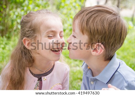 Boy trying kissing cheerful girl outdoor