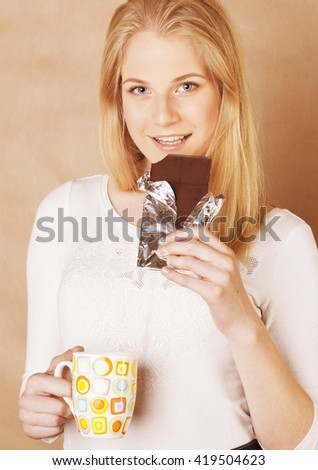 young cute blond girl eating chocolate and drinking coffee close up