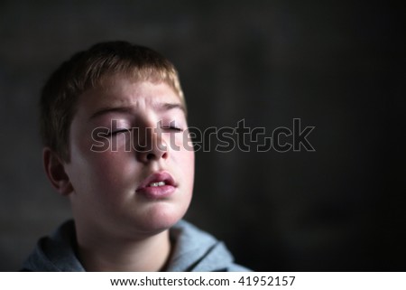 Young boy looking up with hope in his eyes against grunge background flash lit 3 light sources