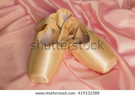 Ballet shoes on delicate pink silk background