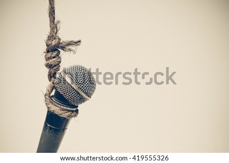 Broken microphone hung on a rope - Threatening press freedom concept Royalty-Free Stock Photo #419555326