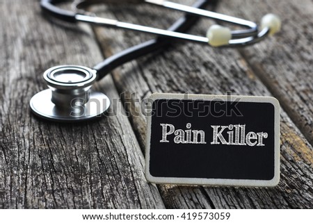 Medical Concept-Pain Killer word written on blackboard with Stethoscope on wood background