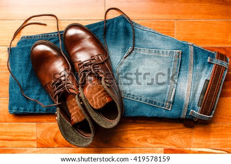 Jeans with brown leather boots over wooden floor 