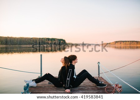 Young happy couple resting on a pier on a sunny summer day. love concept