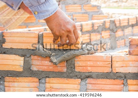 Clutching a brick wall panel is made up by bricks and mortar, concrete medium of binders.