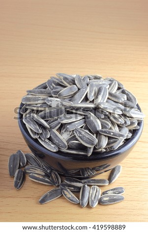 pile of sunflower seeds in a bowl on the wooden background 