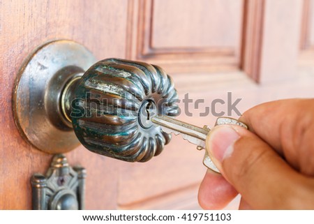Hand hold house key to locking or unlocking the door Royalty-Free Stock Photo #419751103