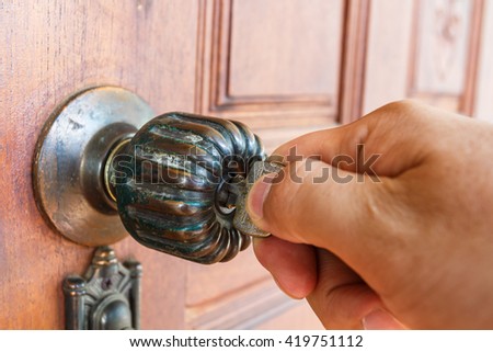 Hand hold house key to locking or unlocking the door Royalty-Free Stock Photo #419751112