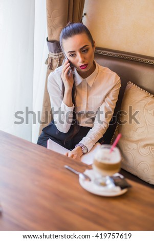 Portrait of young attractive business woman with notebook and pen relaxing in restaurant.