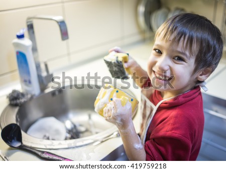 A little cute boy washing dishes Royalty-Free Stock Photo #419759218
