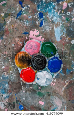Photo of a artists palette loaded with various colour paints on the wood table background