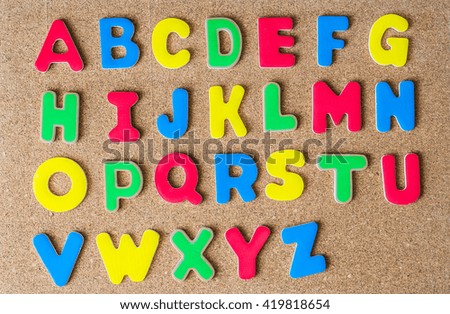 Colorful wooden capital letter alphabet on cork board
