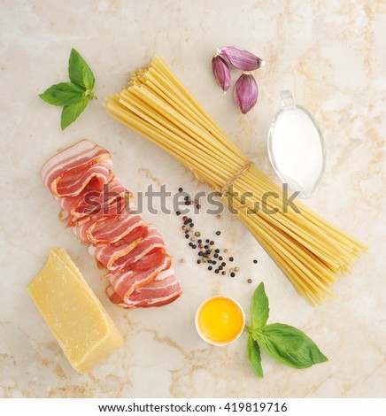 set of products for pasta Carbonara - spaghetti, bacon, cream, Parmesan cheese, Basil, egg, garlic, spices - on a marble background, top view