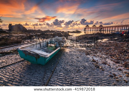 Beautiful sunrise over the sea during low tide with boat in foregound in Tanjung Balau, Malaysia