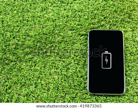Fully charged sign on smart phone on grass background