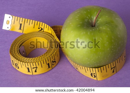 Granny Smith Green Apple with a bright yellow tape measure represents the concepts of diet and healthy lifestyle. Perhaps this is your New Year's Resolution?