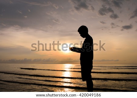 Man silhouette using a mobile phone.Background sunset over the sea