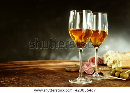 Two glasses of sherry served with tasty traditional Spanish tapas of olives, salami and fresh bread on an old wooden table with copy space Royalty-Free Stock Photo #420056467