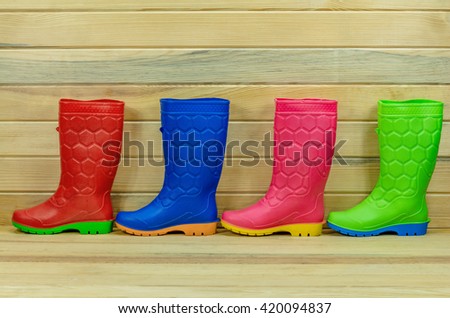 colorful rain boots on a wood background.
