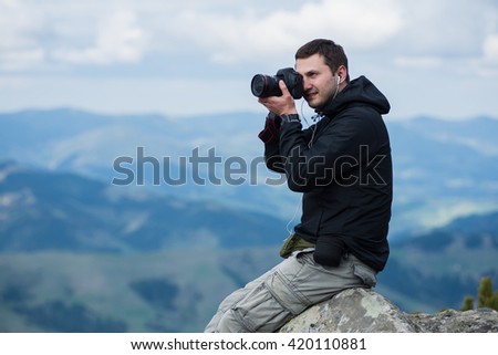 Nature photographer with digital camera on top of the mountain. 
