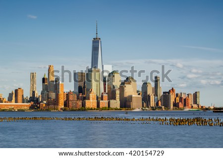 New York City Manhattan Financial District skyscrapers at sunset with Hudson River and old wooden pilings. Lower Manhattan skyline