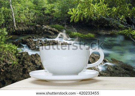 White coffee cup with blur background image of waterfall.