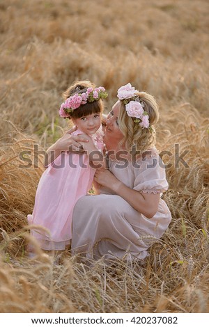 Mother and daughter hugging on her head a garland of roses, soft image