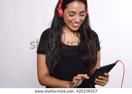Young beautiful woman listening to music with her tablet indoor. Isolated white background.