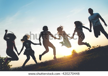 Group of people jumping outdoors; sunset 