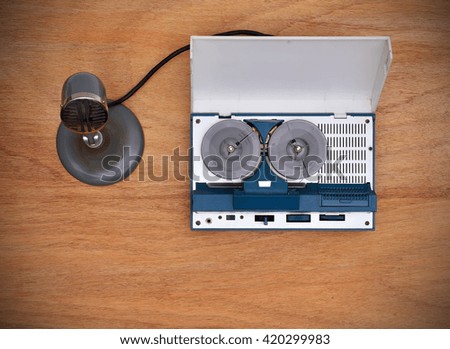 Reel tape recorder and microphone on wooden table. View from above