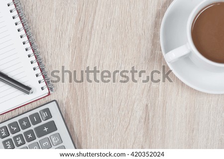 blank notebook with pen and calculator and a cup of black coffee on a wooden background. top view and copy space for text