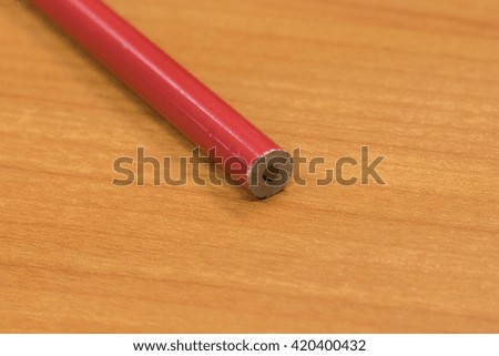 Red Pencil on Wood Background