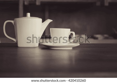 Coffe cup and Coffee pot on the wooden table. Image is a vintage effect and some noise added. Soft focus.In Romantic black and white color.
