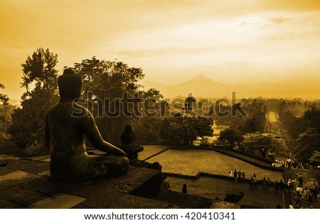 Seated Buddha welcomes sunrise on Buddist Temple Borobudur at Sunrise. Yogyakarta, Indonesia.