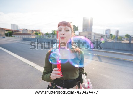 Half length of a young handsome caucasian redhead woman playing with bubble soap, blowing - childhood, youth concept - wearing green shirt