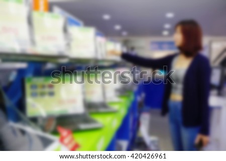 blur image of computer notebook store, Asian girl customer choosing laptop in consumer electronics store