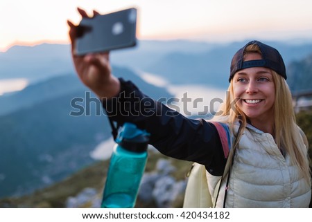 Young traveler taking a selfie picture on top of a mountain