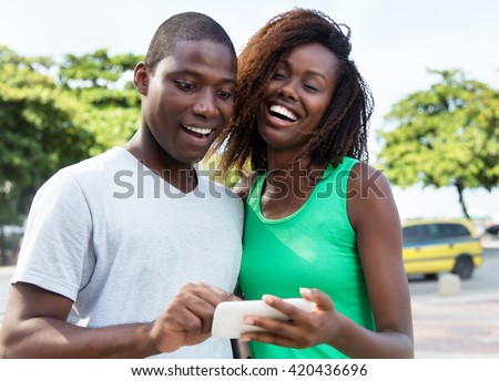 Happy african american couple showing pictures on phone
