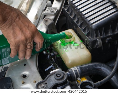 closeup of a man hand refill coolant into radiator engine Royalty-Free Stock Photo #420442015