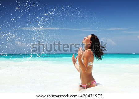 Happy woman on the beach, playing in the sea, splashing water, enjoying active summer vacation, Caribbean Sea, Cancun, Mexico, North America