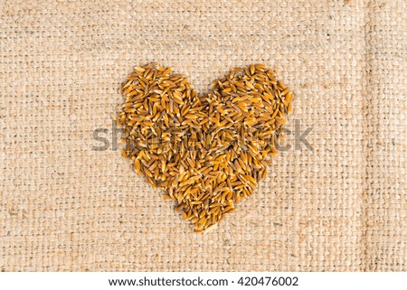 Heart made by rice on hemp sack background.