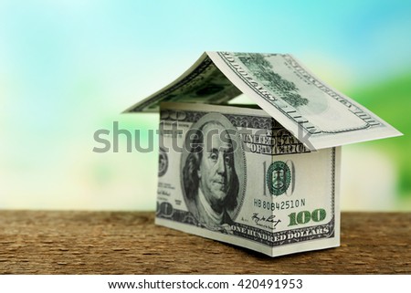 Money house on wooden surface, close up