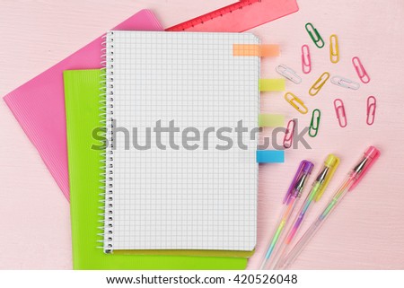 Office set with notebooks, colored pens and clips on pink background