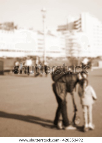 Blurry focus scene of mother and child walk on the street among coast town background represent motherhood concept related idea.
