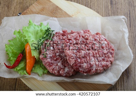 Raw burger cutlet with thyme and pepper