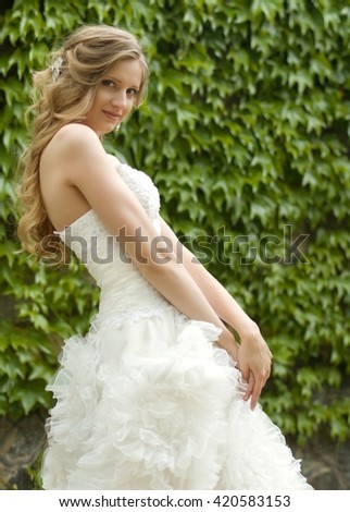 Beautiful bride with stylish make-up in white dress in spring garden